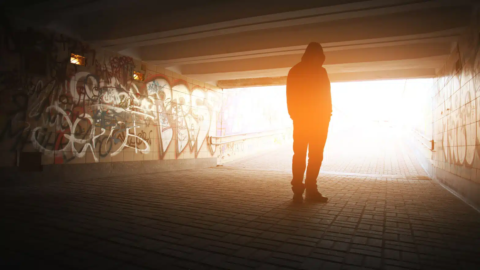 A man stands alone under a bridge - 10 Signs of Addictive Behavior